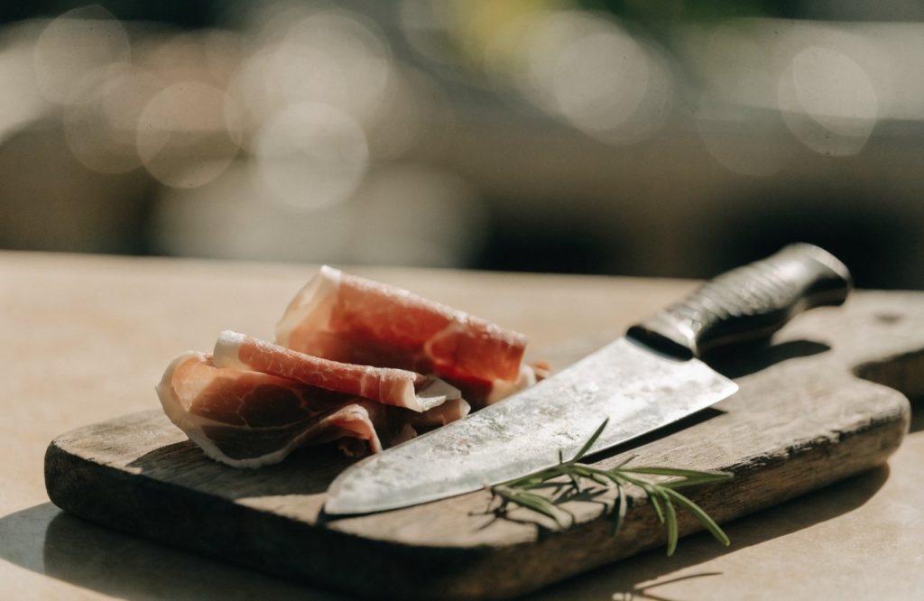 Immagine illustrativa di un tagliere di legno con coltello e salumi — non raffigura il luogo