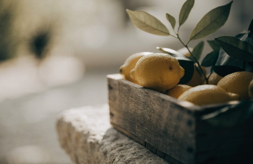 Immagine illustrativa di limoni appena raccolti in una cassetta di legno — non raffigura il luogo